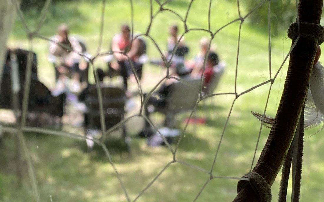 Capteur de rêves devant un cercle de participants en plein air